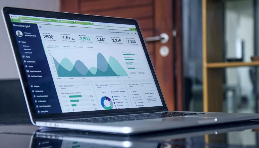 A silver laptop on a desk displaying report metrics and graphs.
