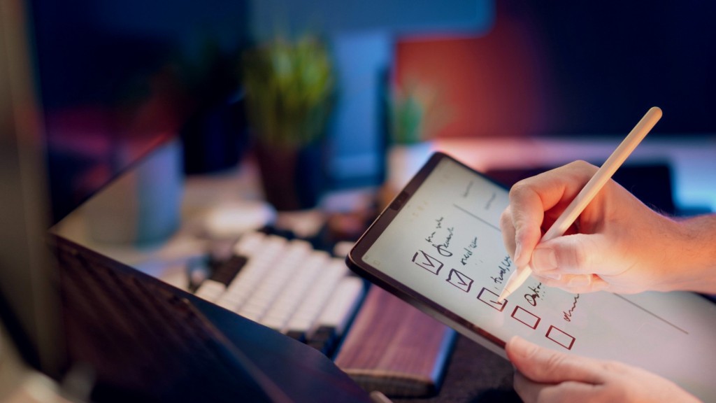 A hand writing on a tablet with a stylus.